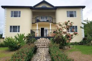 una grande casa bianca con una scala davanti di Farmhouse Estate 30mins from Ocho Rios/Kgn a Knowles