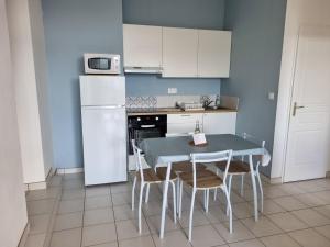 a kitchen with a table and chairs and a refrigerator at La Cabane de l'Océan à 100 m de la plage in Mimizan-Plage