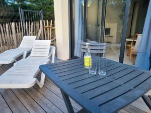 a blue picnic table with two glasses and a bottle at A 200m de la plage - L'Océan - in Mimizan-Plage