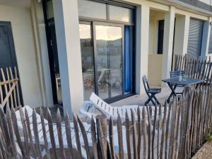 a wooden fence with a table and a chair on a porch at A 200m de la plage - L'Océan - in Mimizan-Plage