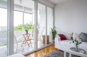 a white living room with a couch and a table at Relax Central Apartment in Zagreb