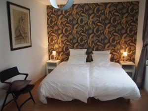a bedroom with a white bed with a black and gold wallpaper at L'Escale 80 in Amiens
