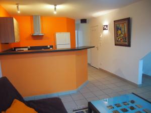 a living room with an orange wall and a kitchen at L'Escale 80 in Amiens