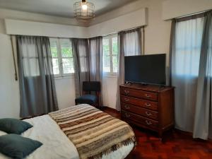 um quarto com uma cama e uma televisão numa cómoda em Departamento Mendoza em Mendoza