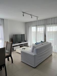 uma sala de estar branca com um sofá e uma televisão em Praia do Forte - Apartamento no Iberostar belíssimo em Mata de São João