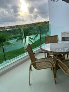 een balkon met een tafel en stoelen en uitzicht op de oceaan bij Praia do Forte - Apartamento no Iberostar belíssimo in Mata de Sao Joao