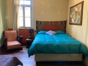 um quarto com uma cama azul e uma cadeira em Hostal brons em Valparaíso