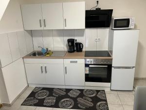 a kitchen with white cabinets and a sink and a microwave at FW am Park 1 in Holzminden