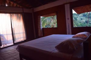 1 dormitorio con 1 cama grande y 2 ventanas en Casa Sakal, en Puerto Ángel