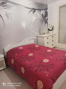 1 dormitorio con 1 cama con colcha roja en Chambre d hôte à 20 min de VERSAILLES, en Le Mesnil-Saint-Denis