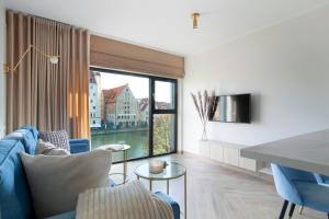 a living room with a blue couch and a large window at Elite Apartments Rezydencja Wintera in Gdańsk