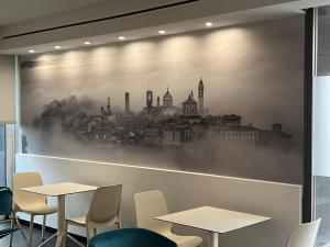 a wall mural of a city with tables and chairs at San Valentino Hotel in Villa di Serio