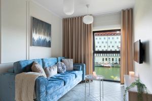a living room with a blue couch and a window at Elite Apartments Rezydencja Wintera in Gdańsk