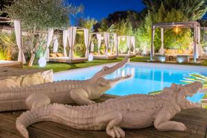 two statues of crocodiles next to a swimming pool at Buddha Beach Thoiry in Thoiry