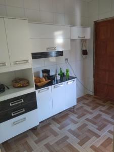 a kitchen with white cabinets and a wooden floor at Casa familiar in Angra dos Reis