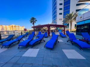 un grupo de sillas azules en un patio con cenador en Exquisite, luxe 1BD Apartment, Unparalleled Sea Views, Prime Dubai Marina Location & Full Kitchen by "La Buena Vida Holiday Homes, en Dubái