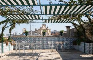 Eine Terrasse mit Tischen und Stühlen unter einem schwarz-weißen Sonnenschirm in der Unterkunft Palazzo Luce in Lecce