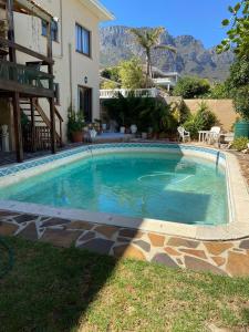 a swimming pool in front of a house at Living In Camps Bay Blue in Cape Town