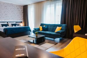 a living room with a blue couch and a bed at Hotel Auris in Szeged