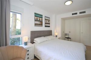 Un dormitorio blanco con una cama y una silla. en Estepona Port Apartment SOL, en Estepona 16 fotos más