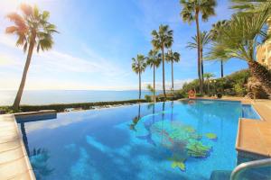 una piscina con palmeras y el océano en Estepona Port Apartment SOL, en Estepona