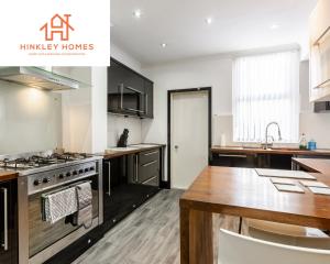 a kitchen with a stove top oven next to a table at Supersized 5bed - Free parking - 8 beds - Anfield - By Hinkley Homes Short Lets & Serviced Accommodation in Liverpool
