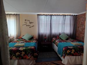 two beds in a room with windows and curtains at KHAYA LANGA Guest House & Contractors Accommodation in Machadodorp