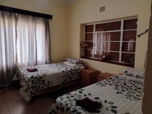 Machadodorp的住宿－KHAYA LANGA Guest House & Contractors Accommodation，带窗户和两张床的宿舍间内的两张床