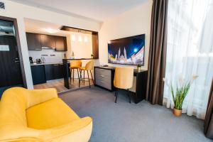 a living room with a yellow chair and a kitchen at Hotel Auris in Szeged