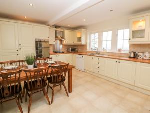uma cozinha com armários brancos e uma mesa e cadeiras de madeira em Lower Cowden Farm em Bakewell
