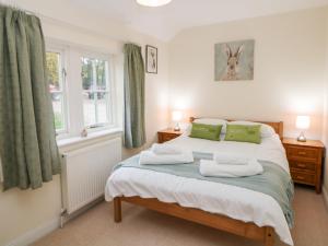 1 dormitorio con 1 cama con cortinas verdes y ventana en Lower Cowden Farm, en Bakewell