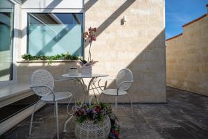 un patio con tavolo, sedie e finestra di Profumi di Primavera Luxury Rooms a Matera
