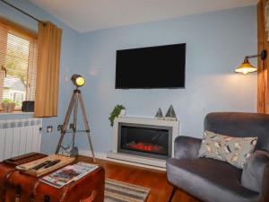 a living room with a fireplace and a tv on the wall at Number 10 Puffin Cottage in Camelford