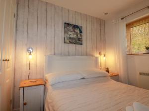 a bedroom with a white bed and a wooden table at Number 10 Puffin Cottage in Camelford