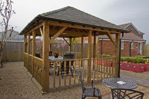a wooden gazebo with a table and chairs at Meals Farm - Courtyard Room in North Somercotes