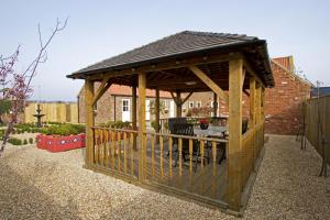 a wooden gazebo with a table in a garden at Meals Farm - Courtyard Room in North Somercotes