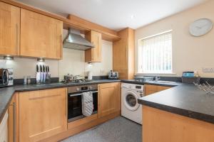 a kitchen with wooden cabinets and a washer and dryer at Apartment 8 in Worksop