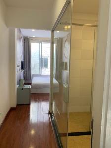 un baño con una puerta de cristal que conduce a un dormitorio en Moka's House en Ho Chi Minh