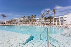 a large swimming pool with palm trees and buildings at Grand Palladium White Island Resort & Spa - All Inclusive in Playa d'en Bossa