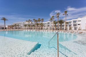 a beach with a pool and a large swimming pool at Grand Palladium White Island Resort & Spa - All Inclusive in Playa d'en Bossa