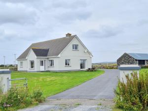 a white house with a gravel driveway at Foregloss Cottage in Ballyconneely