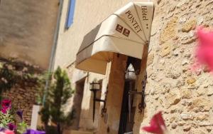 an umbrella on the side of a building with flowers at Hostellerie Maleville, logis hôtel Pontet in Beynac-et-Cazenac