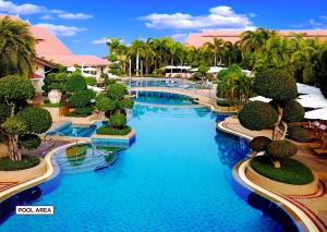 a resort swimming pool with blue water and palm trees at Thai Garden Resort in Pattaya North