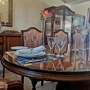 una mesa de comedor con vasos y una flor. en Isabel's B & B en Krugersdorp