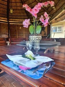 une table avec un vase avec des fleurs roses dans l'établissement Isabel's B & B, à Krugersdorp