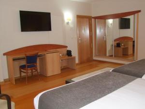 a hotel room with two beds and a desk and a television at Real Ferrol in Ferrol