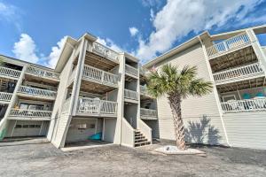 a large apartment building with a palm tree in front of it at Bright Carolina Beach Condo - Walk to Shore! in Carolina Beach