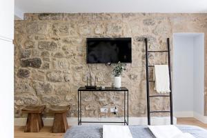 een kamer met een tv aan een stenen muur bij Cimo de Vila 62 by LovelyStay in Porto