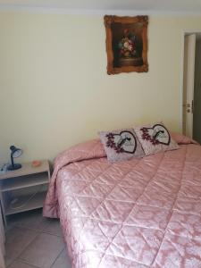 a bedroom with a pink bed with two pillows on it at Apartment Maria in Enna
