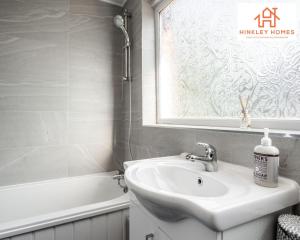 a bathroom with a sink and a tub and a window at Spacious 3 bedroom house with wifi and car parking By Hinkley Homes Short Lets & Serviced Accommodation in Waterloo +42 photos